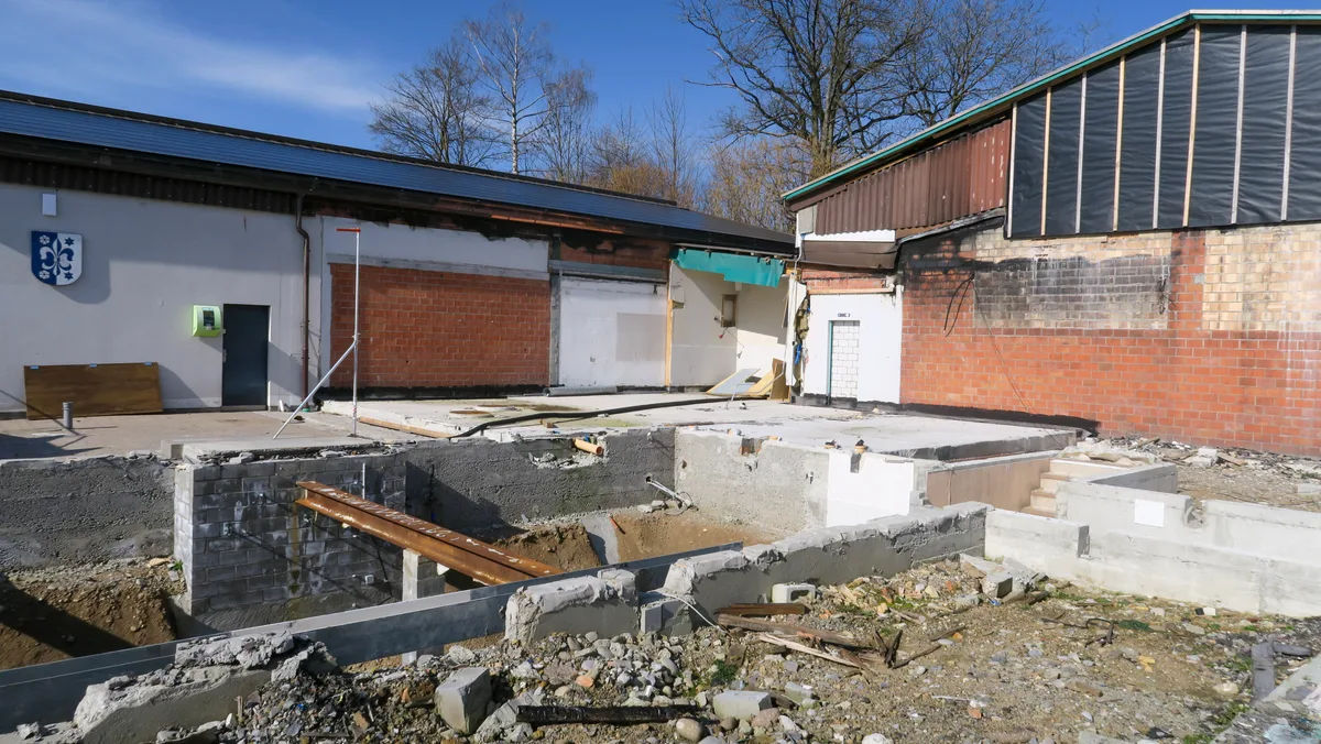 Der ehemalige Standort des Restaurants Speck, Stand März 2026. Rechts die Werkstatt, an die der Ersatzneubau angebaut werden soll. Man sieht ein Loch im Boden und eine Brache mit Baugittern darum und Baugespanne.